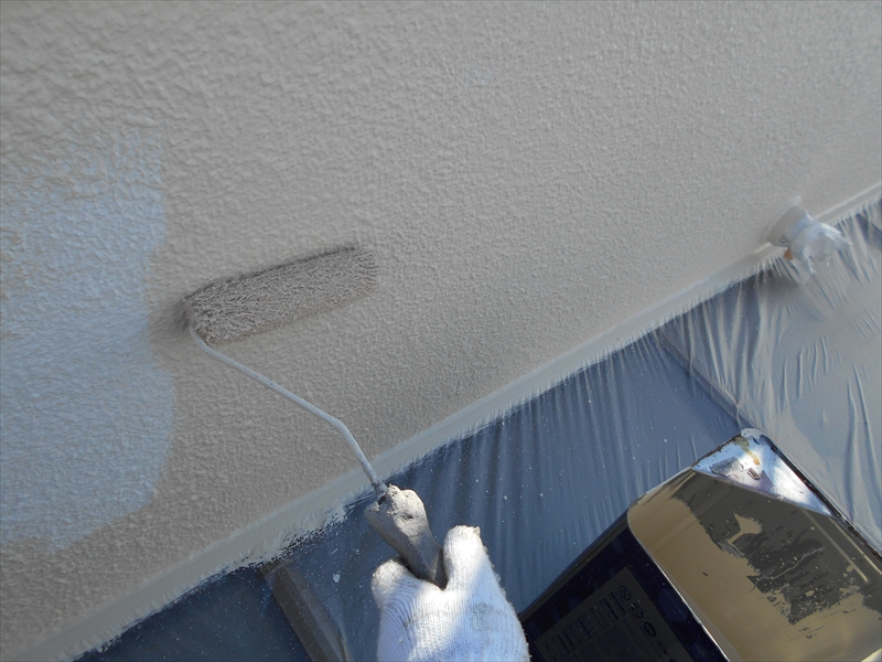 外壁の中塗りのようす。下側に塗料がつかないようにしっかりと養生でカバーしています。