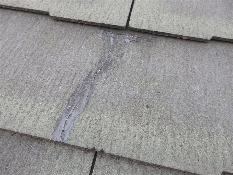 スレート屋根が割れた跡を、コーキング材で補修しています。