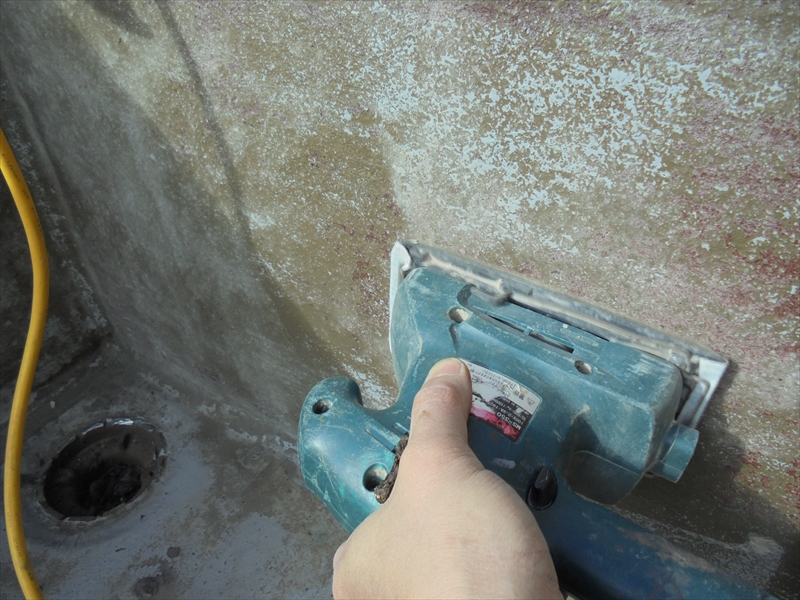 ベランダの防水加工の準備として、立ち上がり部分の古い塗料をサンダーで削り落としています。