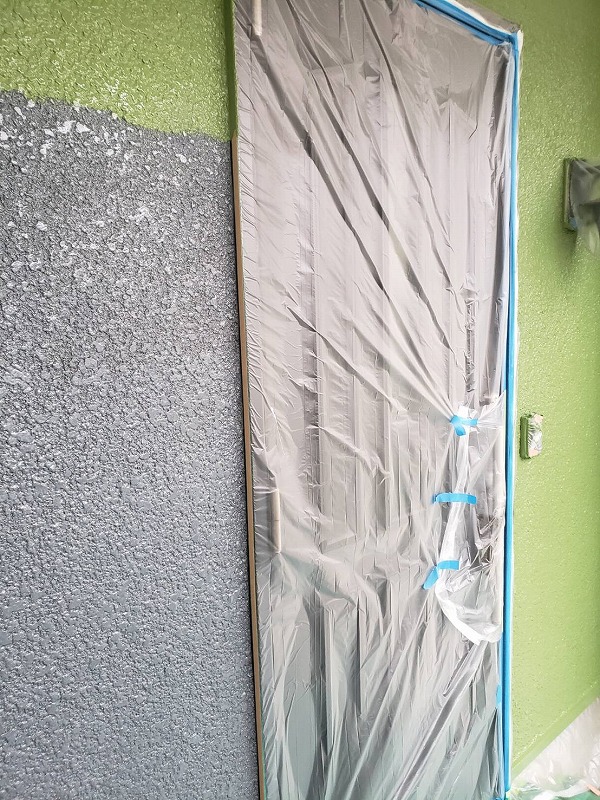 こちらは外壁の中塗りの様子。ドアは開けられるように工夫した上で、塗料がつかないように養生しています。
