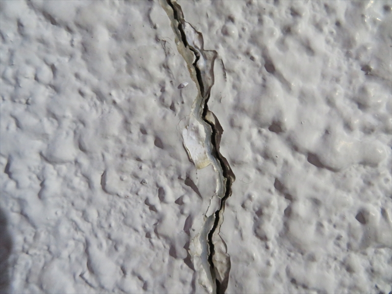 ひび割れた部分をよく見ると、下地のモルタル部分、その上に塗材、前回の塗膜が見えています。