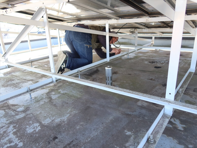 太陽光発電の機材を乗せたまま、防水層の再塗装が可能かチェックしています。